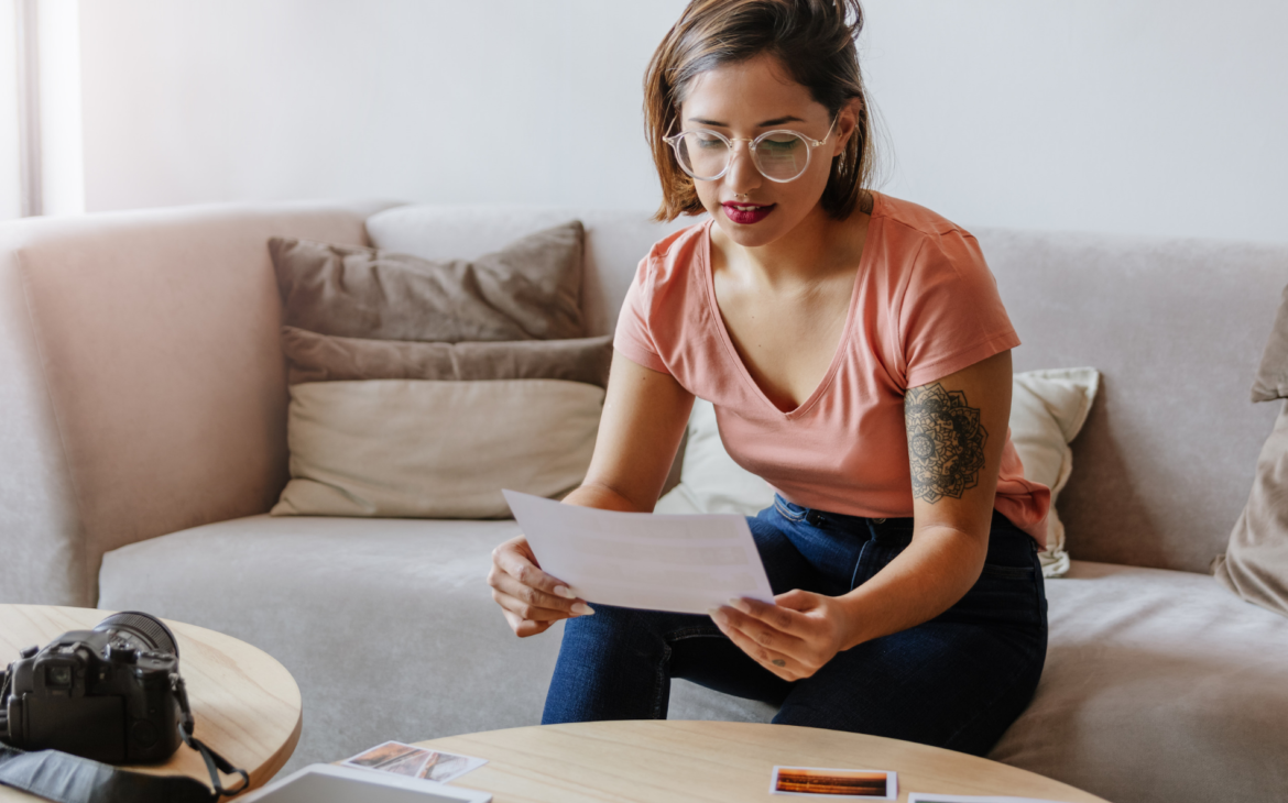 Young woman photographer sat on sofa looking at photos