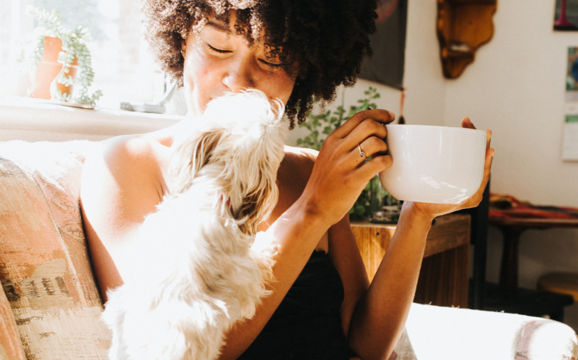 Happy smiling woman resting with cup of tea and pet dog